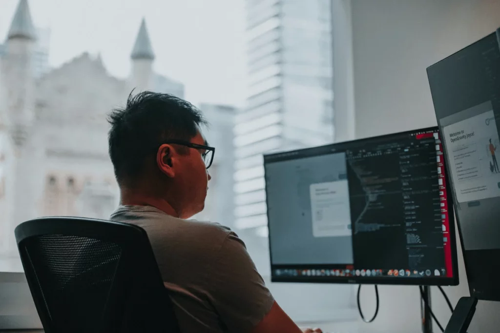 Man coding on dual monitors in modern office.