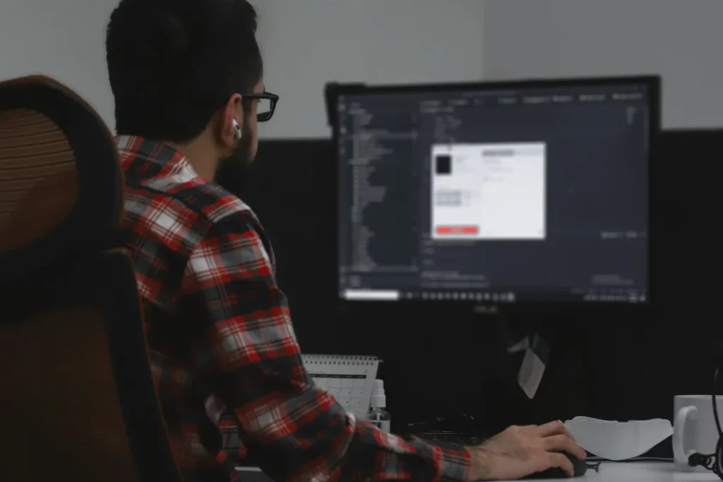 Software developer coding on desktop computer in office.